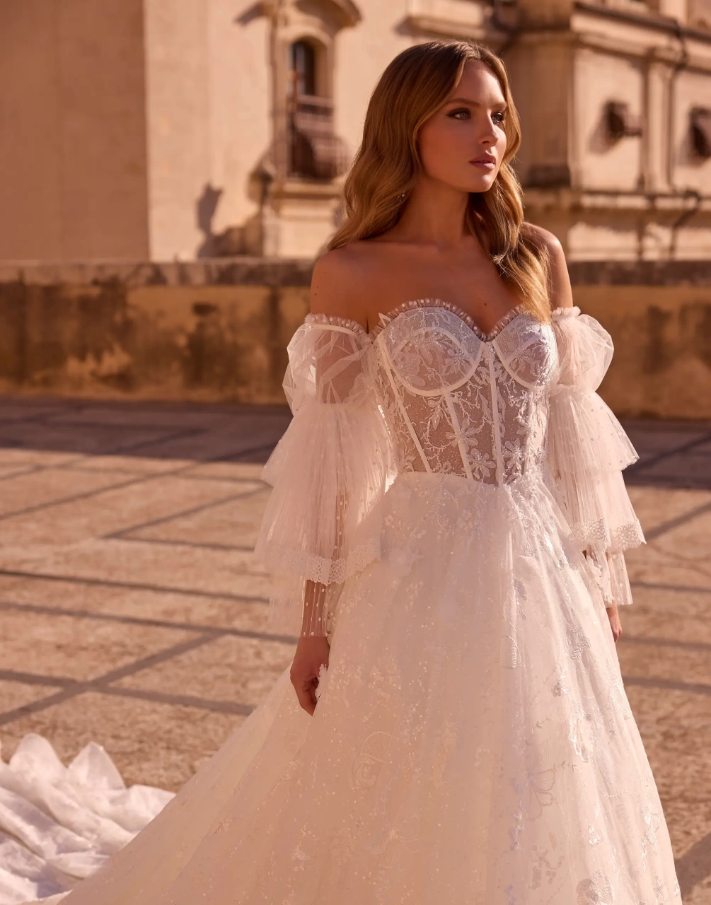 Abito da sposa boho romantico in pizzo con maniche lunghe particolare a balze di tulle, corsetto in pizzo effetto tattoo con stecche a vista, gonna A-line in tulle e pizzo | Lo Specchio Atelier Abiti da Sposa a Verona
