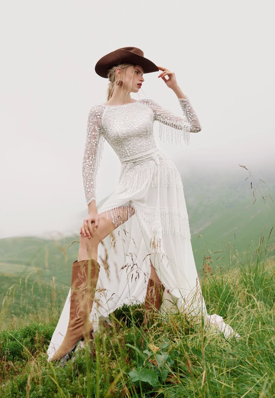 Abito da sposa particolare stile country chic con maniche lunghe effetto tattoo, scollo a barchetta, gonna scivolata con spacco e frange particolari applicate sulle maniche e sulla gonna | Lo Specchio Atelier Abiti da Sposa a Verona