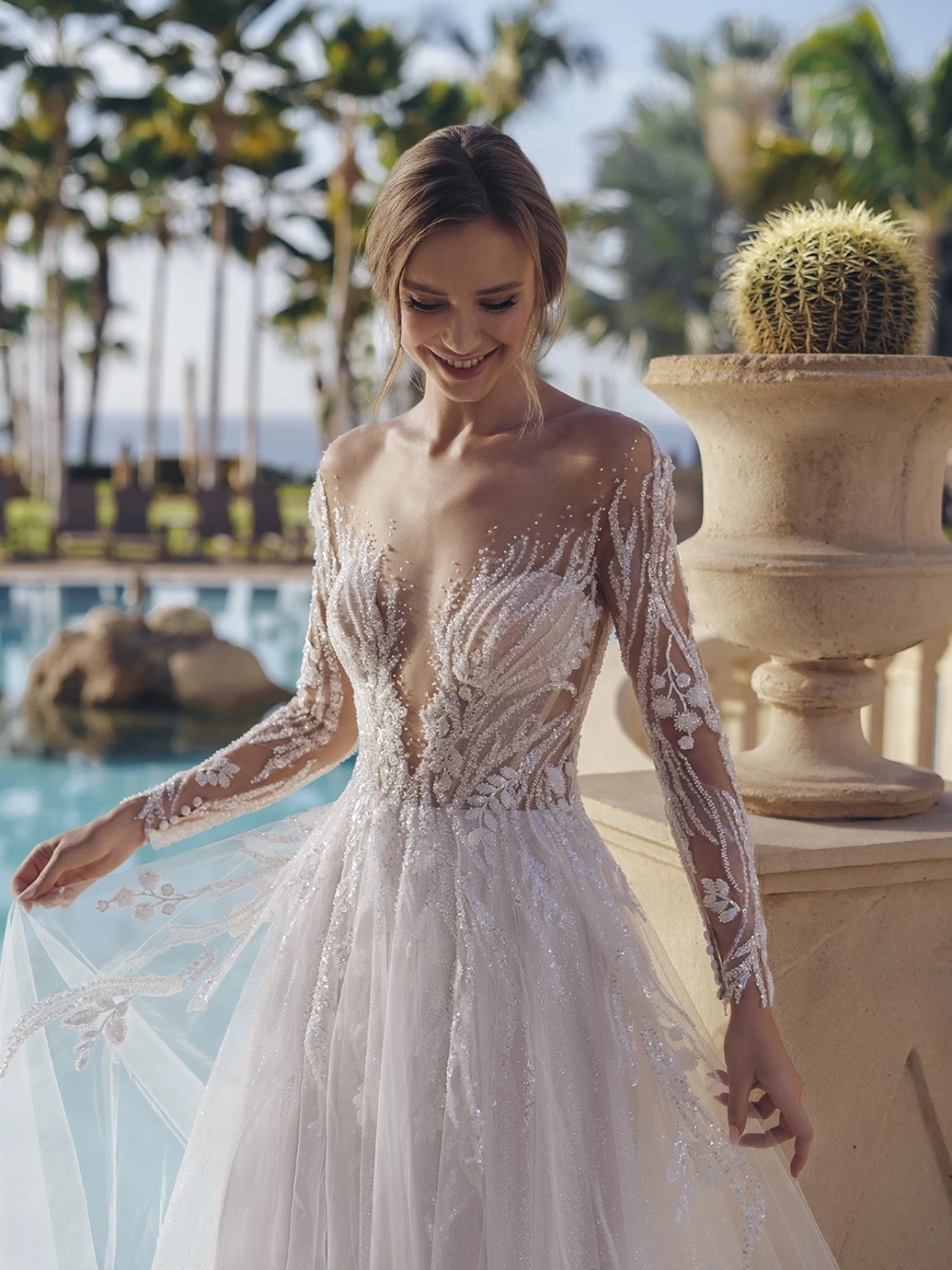 Abito da sposa particolare scivolato con maniche lunghe off-shoulder effetto tattoo, corpino in pizzo floreale effetto tattoo con glitter e cristalli, profondo scollo a V, gonna scivolata in tulle drappeggiato e glitterato con applicazioni di pizzo | Lo Specchio Atelier Abiti da Sposa a Verona