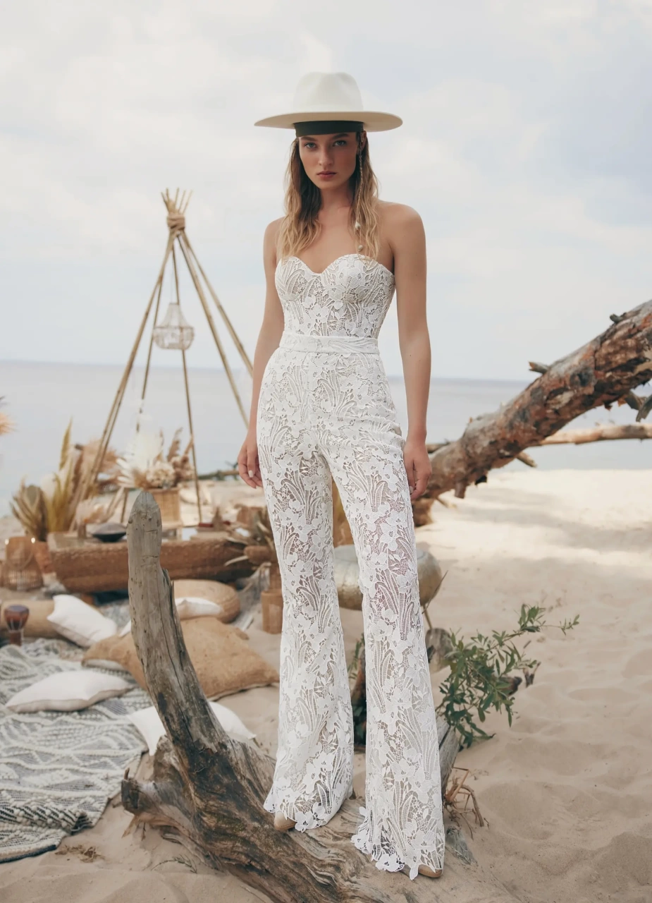 Tuta da sposa particolare stile boho in pizzo effetto tattoo, aderente, pantaloni a zampa, scollo a cuore senza spalline, kimono in tulle trasparente con frange stile country