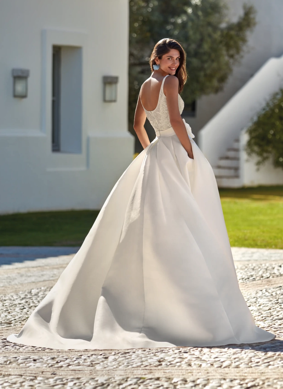 Vestito da sposa corto in pizzo con scollo squadrato e spalline spesse, gonna staccabile ampia e strutturata in mikado con fiocco frontale in pizzo