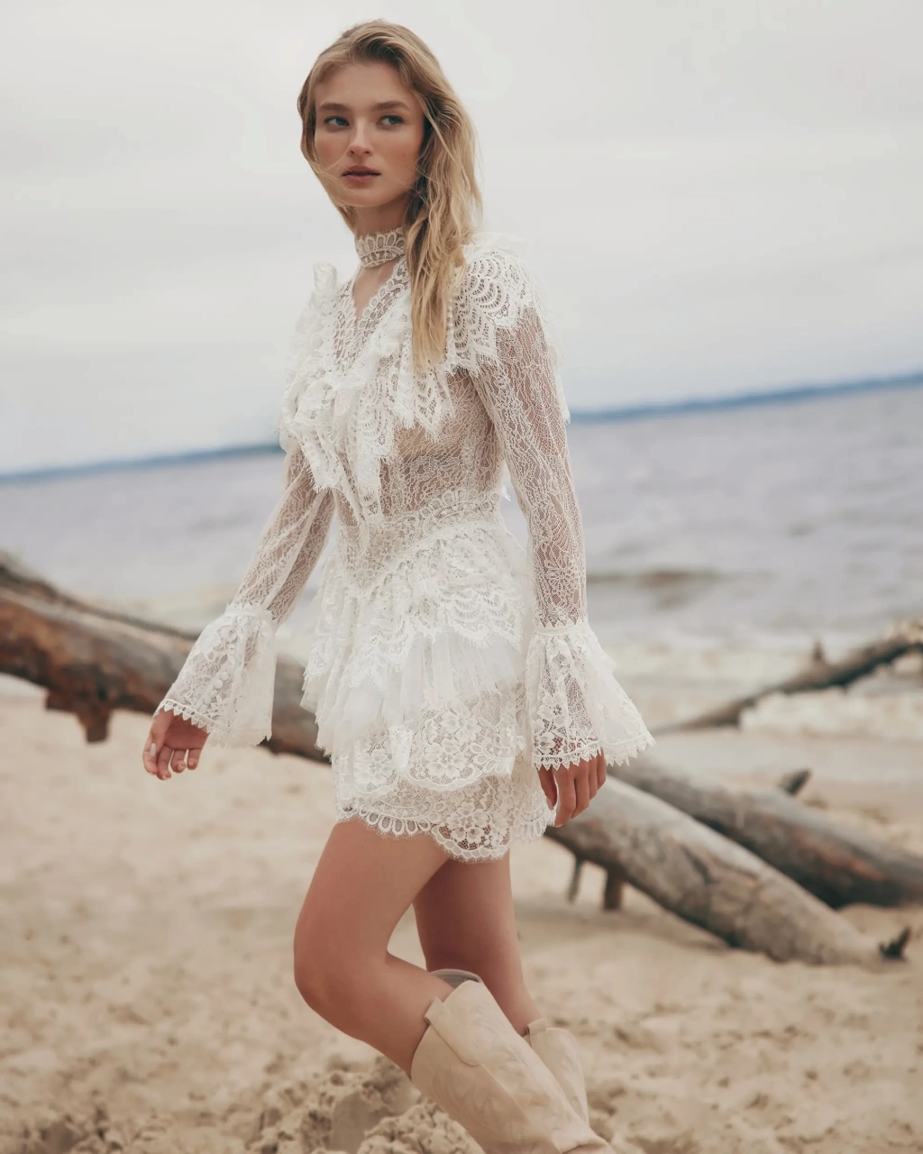 Abito da sposa corto particolare stile boho country in pizzo, maniche lunghe a campana effetto tattoo, colletto alto in pizzo, gonna a balze, lavorazione di balze in pizzo sullo scollo