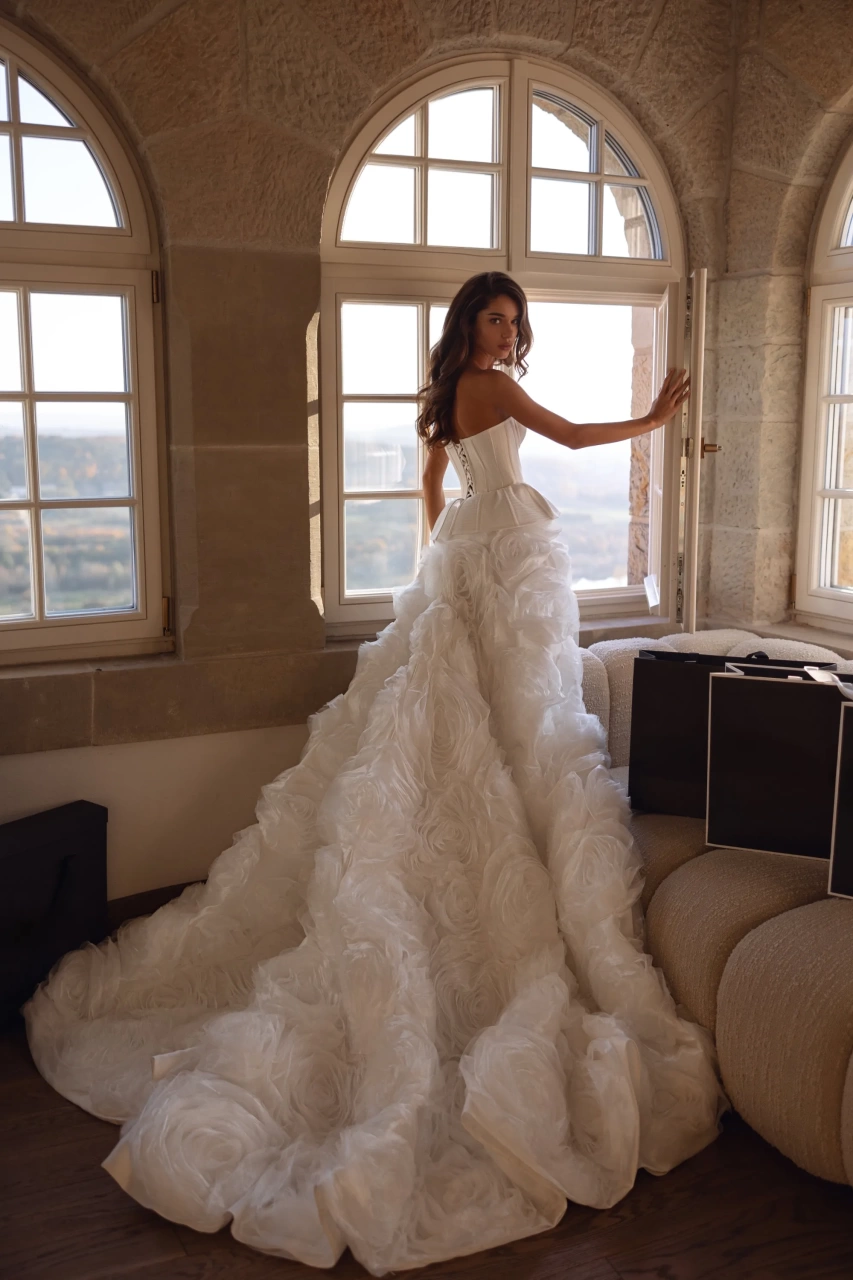 Abito da sposa particolare e scenografico con corpetto steccato in mikado, scollo a cuore senza spalline, fianchi strutturati e gonna particolare con rose 3D in tulle