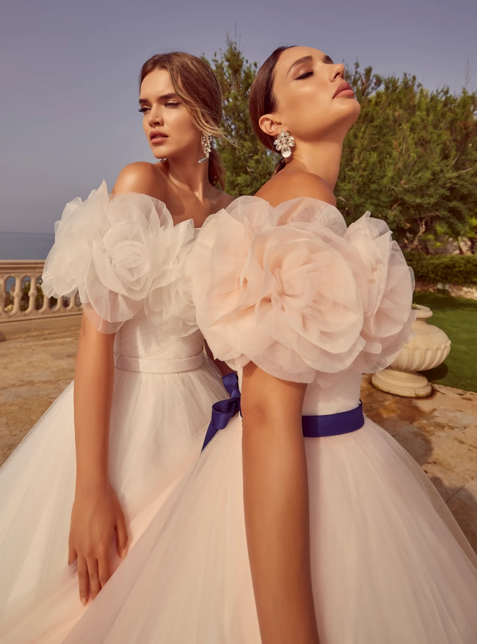 Abito da sposa particolare colorato rosa lussuoso e principesco in tulle, scollo off-shoulder con grandi rose di tulle applicate sia davanti che sulla schiena, fascia in raso viola in vita, gonna ampia in tulle con lavorazione di grandi rose tridimensionali di tulle, disponibile anche in bianco | Lo Specchio Atelier Abiti da Sposa a Verona