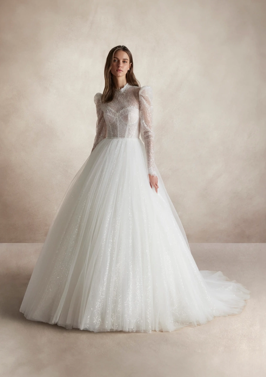 Abito da sposa lussuoso da principella con maniche lunghe a sbuffo in tulle, collo alto, corsetto strutturato con stecche e coppe a vista, gonna ampia A-line in tulle, pizzo ricamato con perle strass e cristalli su tutta la silhouette | Lo Specchio Atelier Abiti da Sposa a Verona