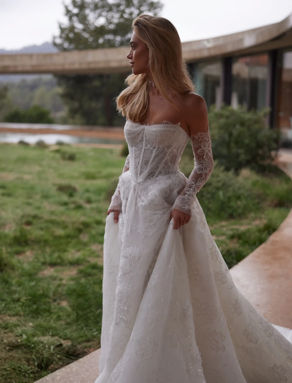 Abito da sposa con maniche lunghe off-shoulder separate in pizzo effetto tattoo, silhouette da principessa con gonna A-line in tulle e pizzo floreale, scollo a cuore, corpino a vita basca con stecche in vista, senza spalline