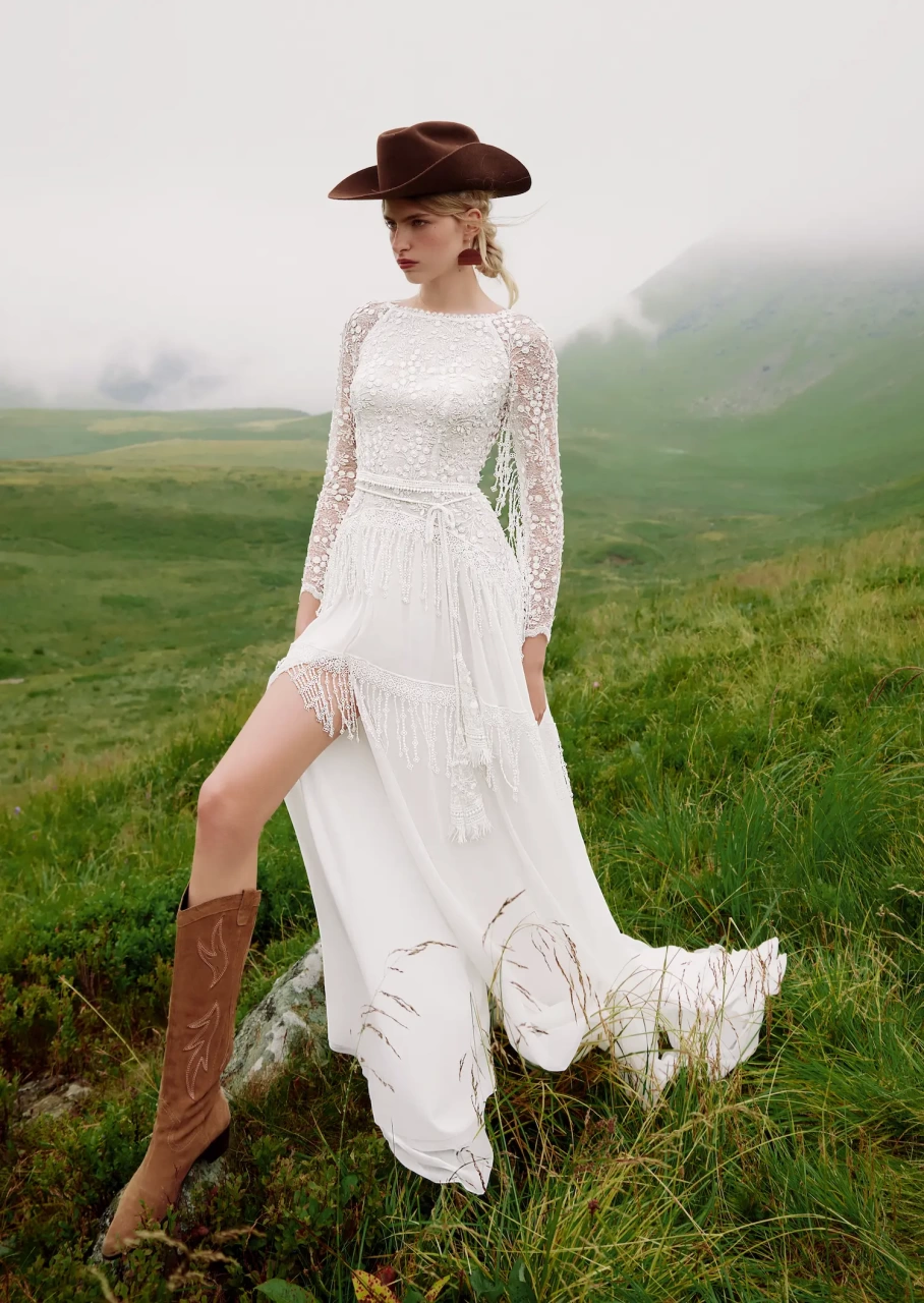 Abito da sposa particolare stile country chic con maniche lunghe effetto tattoo, scollo a barchetta, gonna scivolata con spacco e frange particolari applicate sulle maniche e sulla gonna | Lo Specchio Atelier Abiti da Sposa a Verona