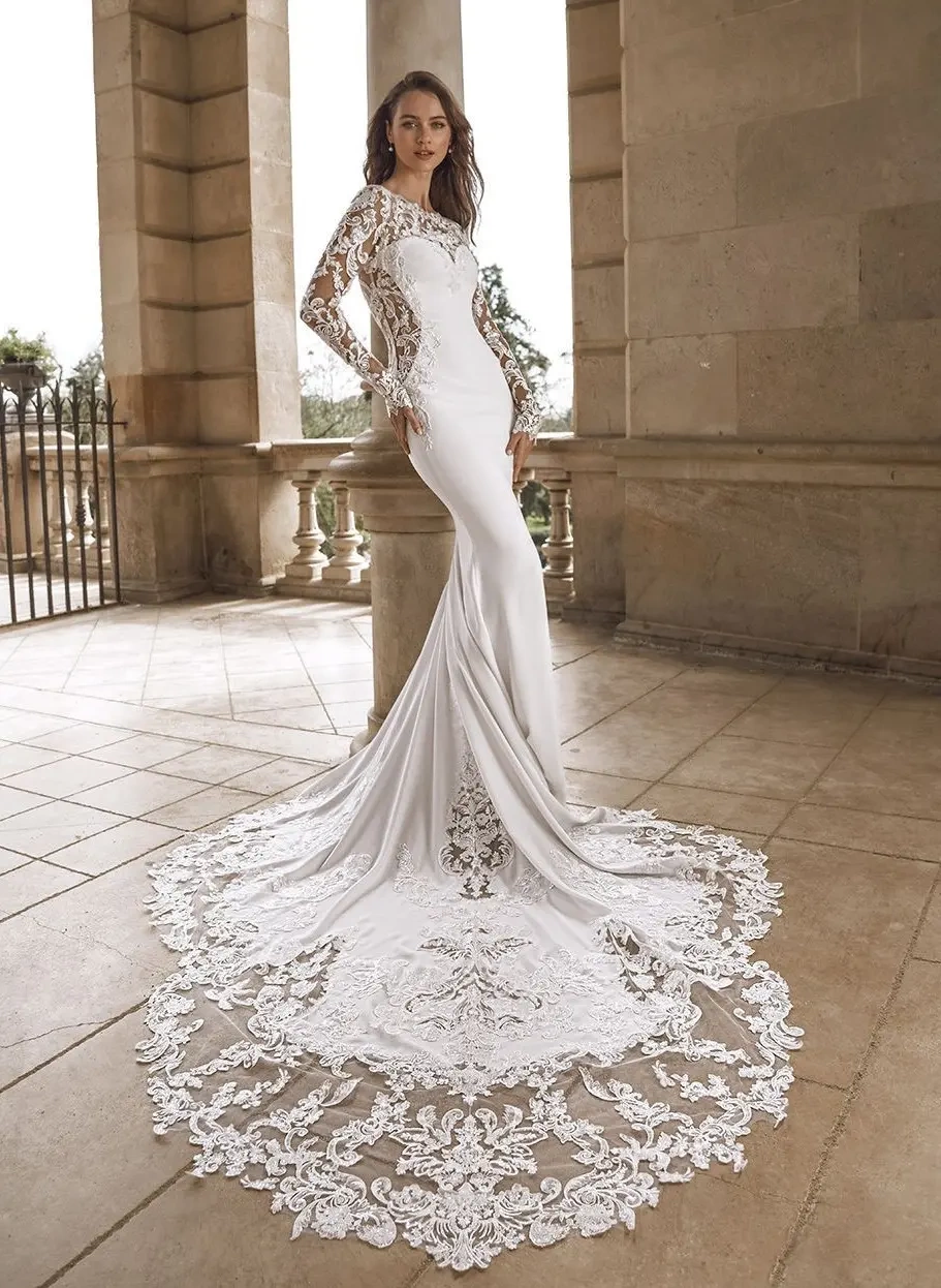 Abito da sposa particolare a sirena in crepe, maniche lunghe e schiena scoperta in pizzo effetto tattoo, fianchi cut-out in pizzo, strascico particolare drammatico con lavorazioni in pizzo