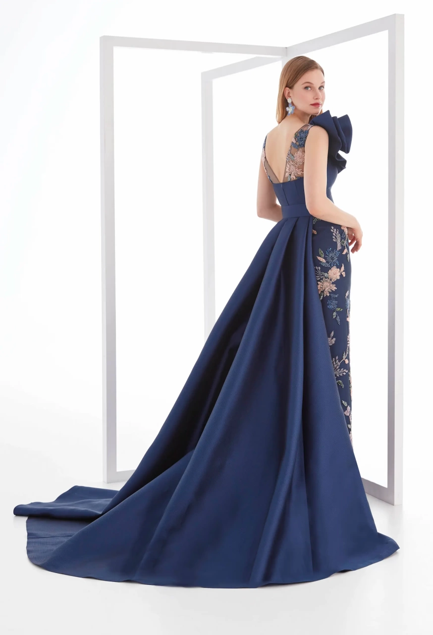 Vestito da cerimonia lungo estivo da donna color blu navy, gonna a sirena con stampa floreale rosa antico, sovragonna ampia e strutturata blu navy, cintura sul punto vita, scollo a barchetta velato e bustino con scollo a cuore e scenografico dettaglio 3D sulla spalla destra - Lo Specchio Atelier Abiti da Cerimonia a Verona