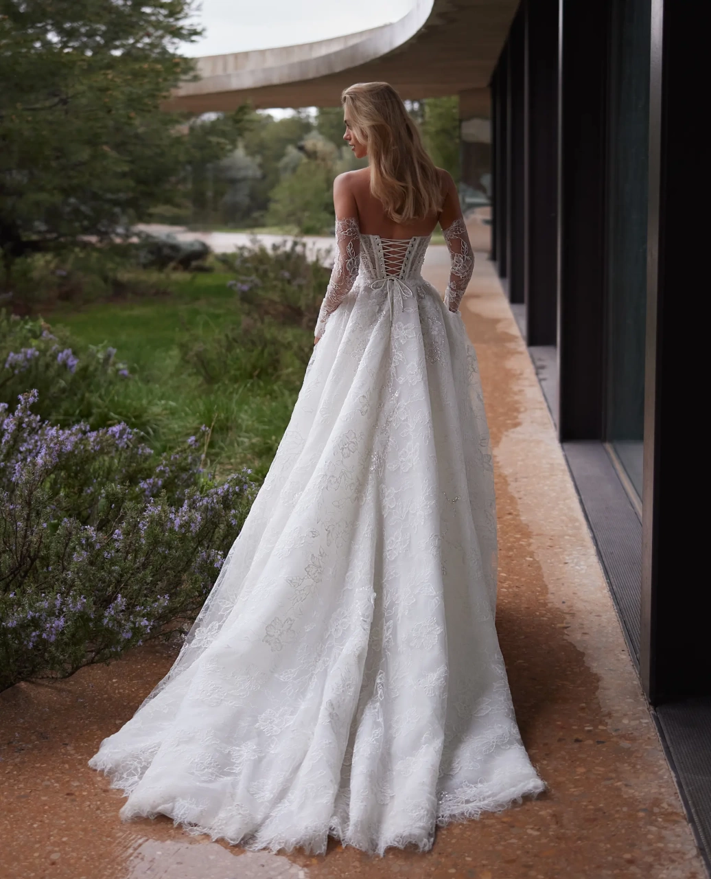 Abito da sposa con maniche lunghe off-shoulder separate in pizzo effetto tattoo, silhouette da principessa con gonna A-line in tulle e pizzo floreale, scollo a cuore, corpino a vita basca con stecche in vista, senza spalline