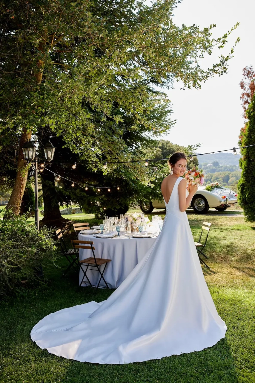 Abito da sposa semplice classico A-line in mikado con scollo a V profondo, senza maniche, schiena scoperta, drappeggio incrociato sul punto vita | Lo Specchio Atelier Abiti da Sposa a Verona