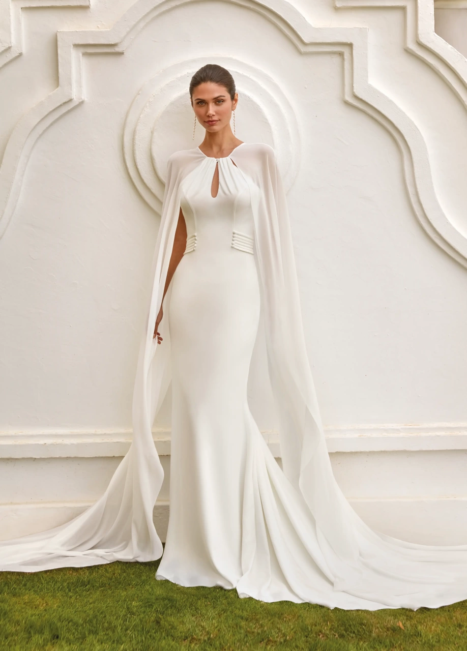 Abito da sposa elegante e raffinato a sirena con scollo all'americana, schiena scoperta, maniche particolari in chiffon che creano un mantello a strascico lungo fino a terra, applicazioni di perle sui fianchi