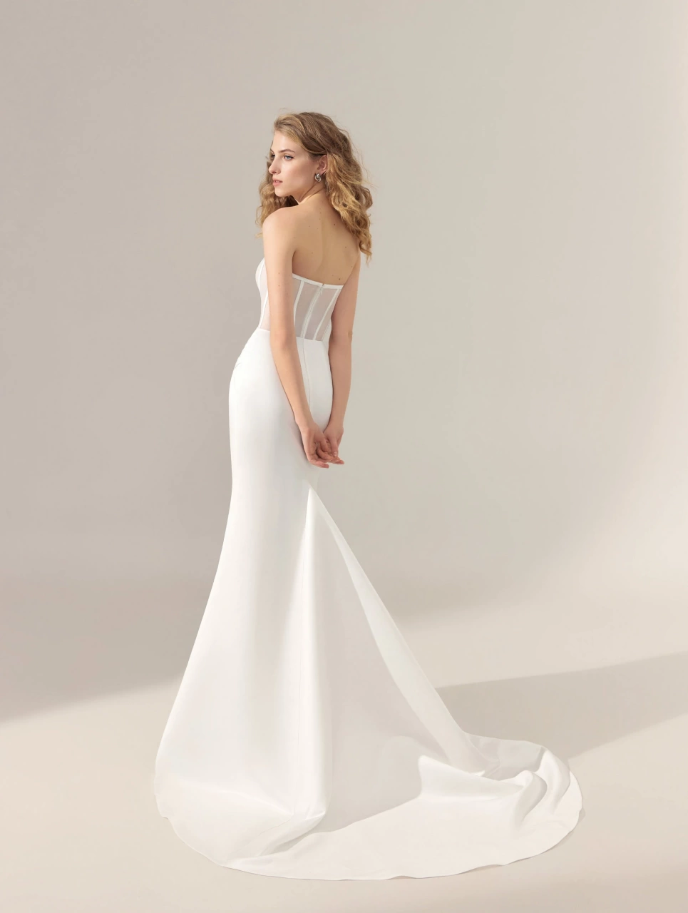 Abito da sposa particolare con corsetto steccato effetto nude e stecche a contrasto, gonna drappeggiata con spacco a portafoglio, strascico staccabile drappeggiato