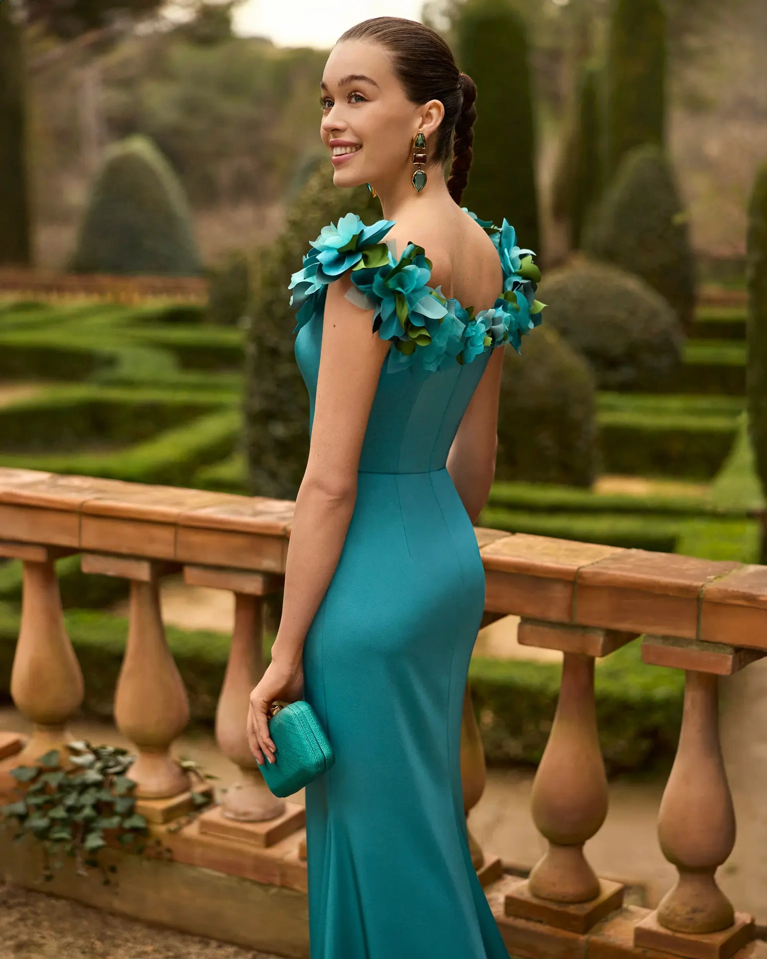 Abito da cerimonia a sirena verde con piccolo drappeggio sulla gonna e spacco sopra al ginocchio, strascico corto, scollo a barchetta con applicazioni 3D di fiori e foglie ton-sur-ton lungo tutta la linea dello scollo sia anteriore che posteriore - Lo Specchio Atelier Abiti da Cerimonia a Verona