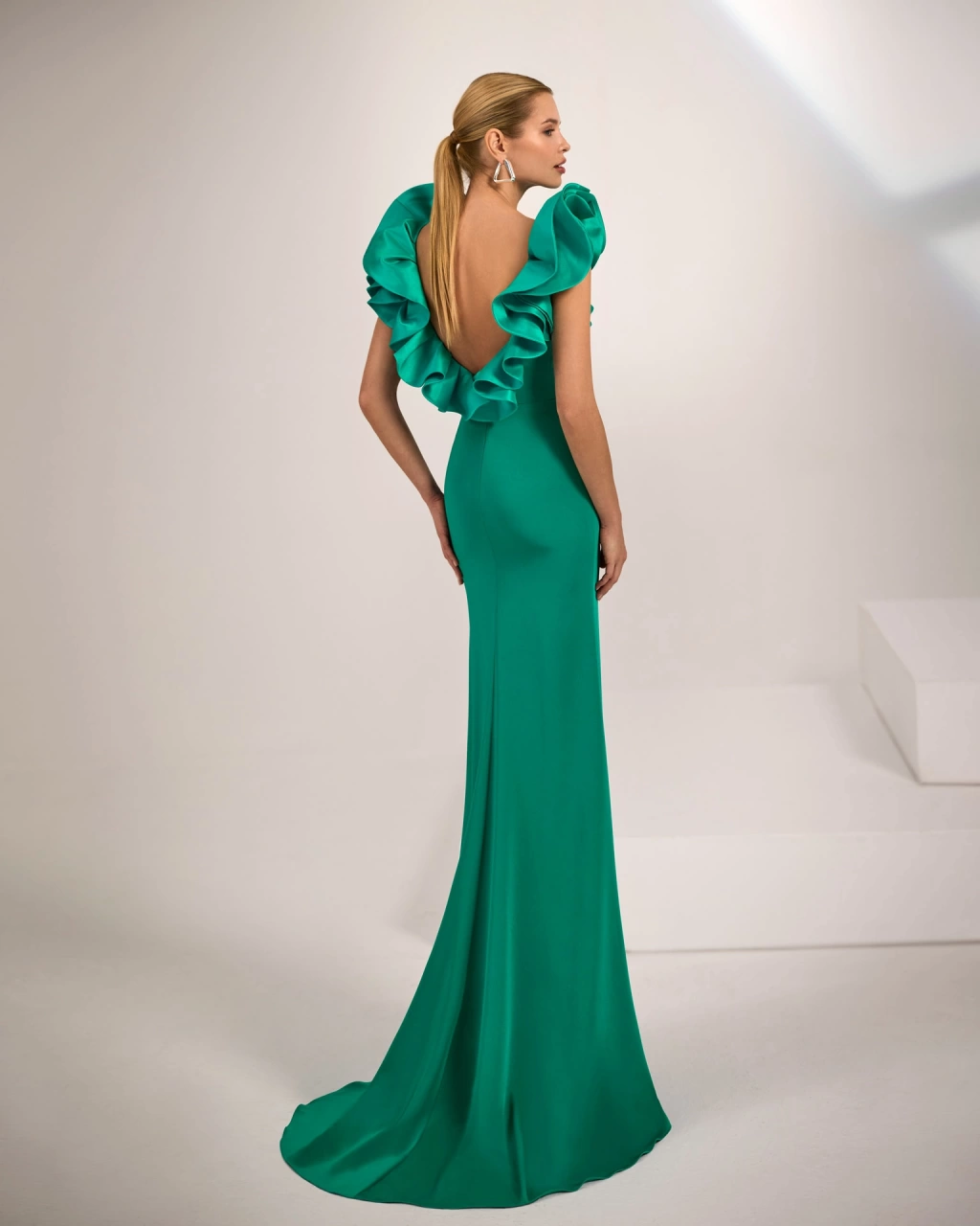 Abito lungo da cerimonia verde smeraldo a sirena in crëpe, scollo a barchetta e schiena scoperta, con un'applicazione di voluminose ruches lungo tutto lo scollo posteriore, gonna con spacco frontale - Lo Specchio Atelier Abiti da Cerimonia a Verona