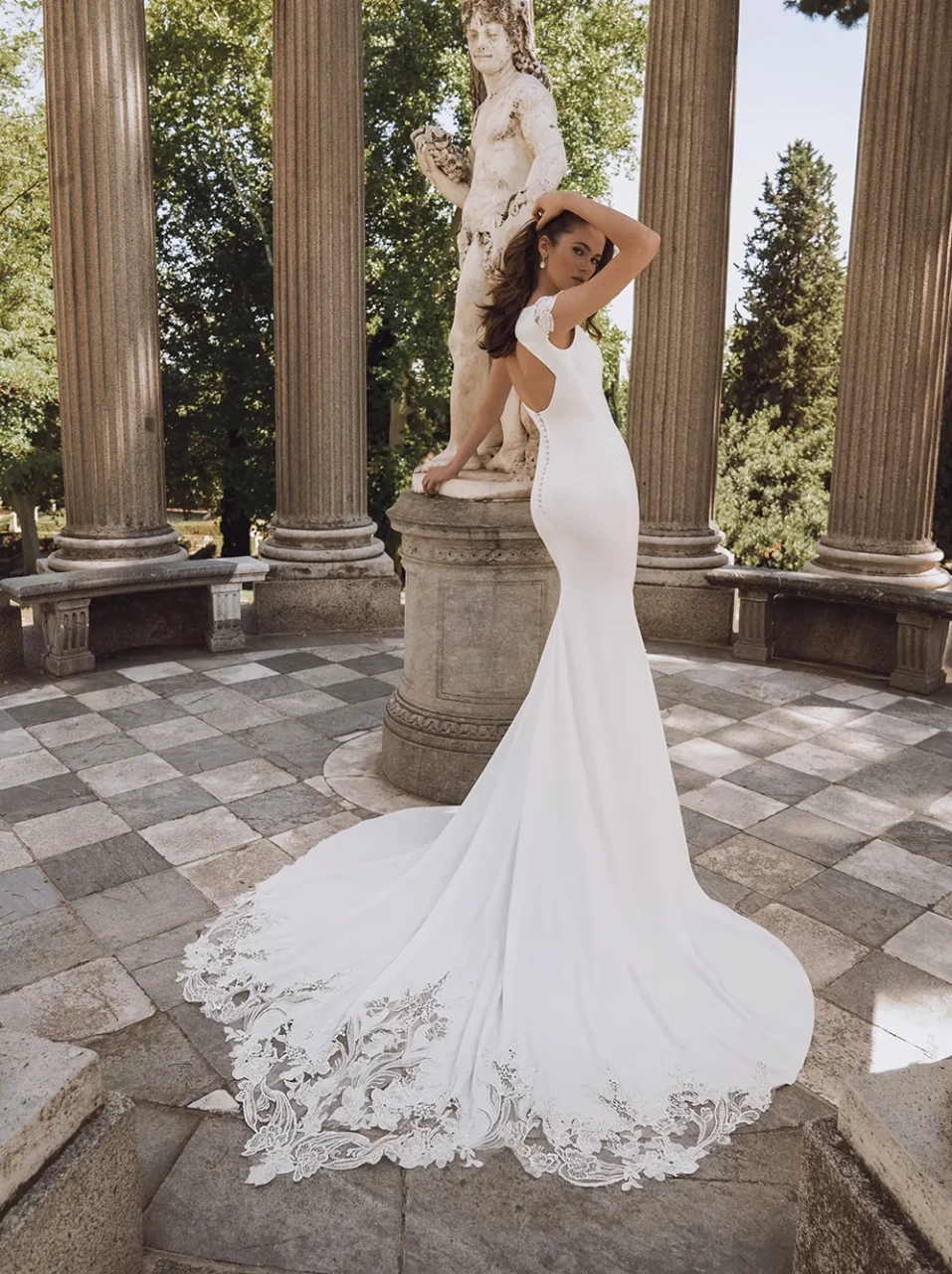 Abito da sposa con maniche corte in pizzo effetto tattoo, schiena scoperta, scollo a barchetta, strascico particolare con lavorazione in pizzo