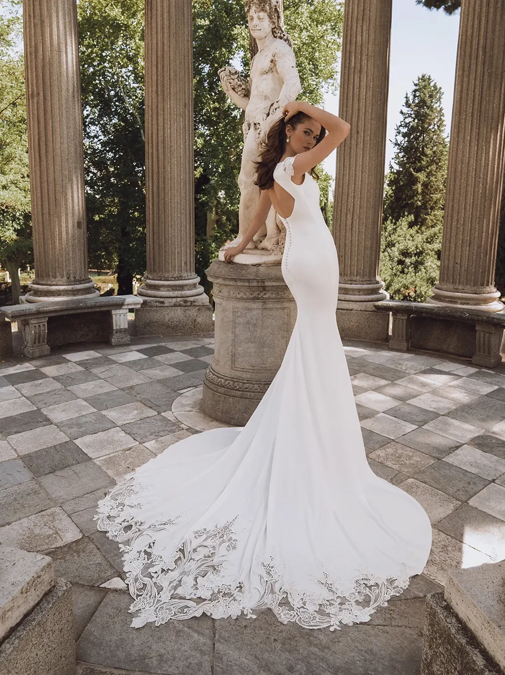 Abito da sposa con maniche corte in pizzo effetto tattoo, schiena scoperta, scollo a barchetta, strascico particolare con lavorazione in pizzo