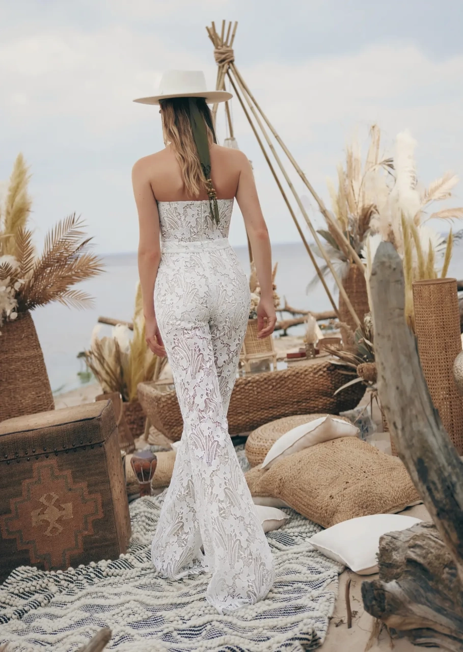 Tuta da sposa particolare stile boho in pizzo effetto tattoo, aderente, pantaloni a zampa, scollo a cuore senza spalline, kimono in tulle trasparente con frange stile country