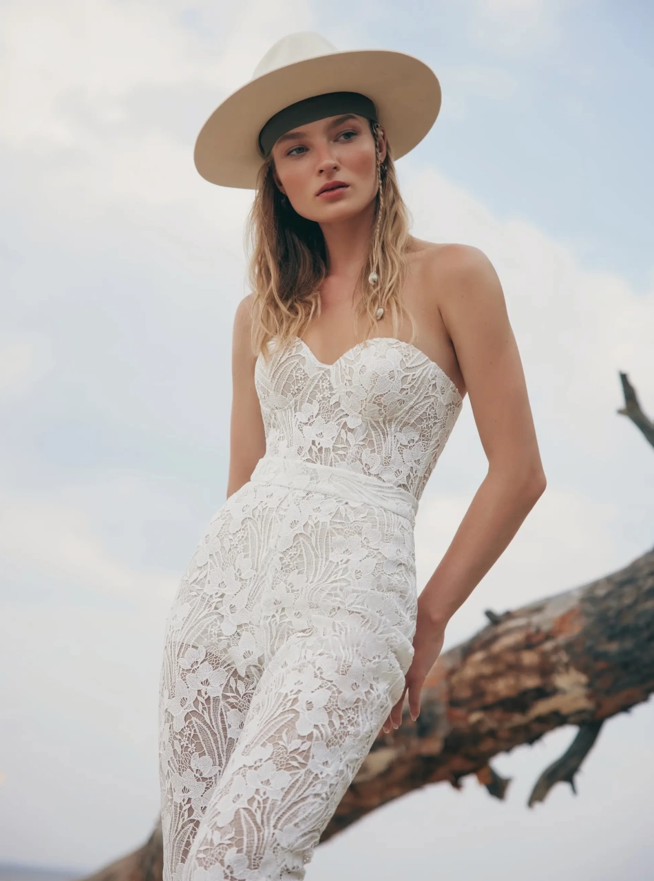 Tuta da sposa particolare stile boho in pizzo effetto tattoo, aderente, pantaloni a zampa, scollo a cuore senza spalline, kimono in tulle trasparente con frange stile country
