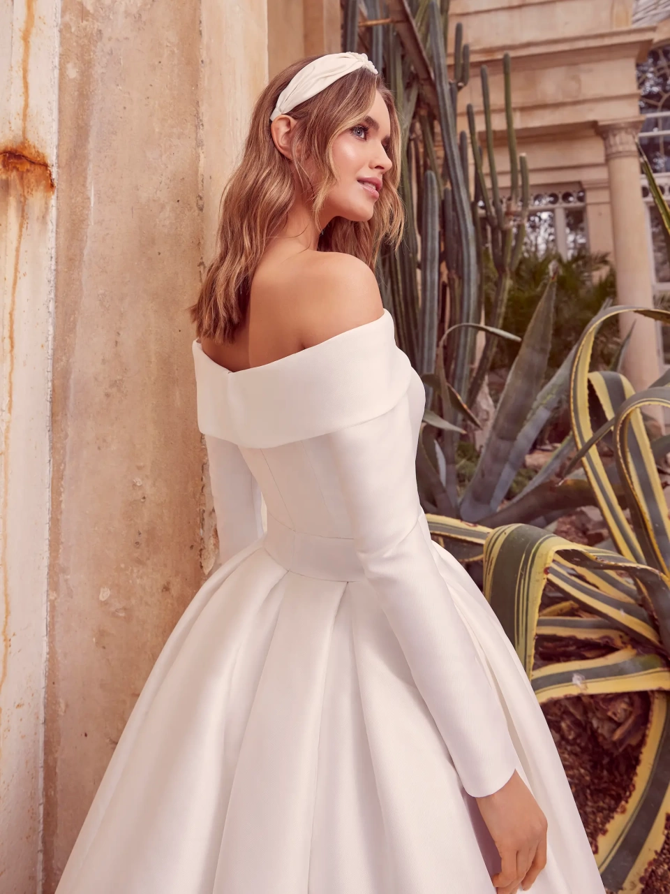 Abito da sposa semplice in mikado con scollo dritto off-shoulder, cintura con fibbia ton-sur-ton, maniche lunghe staccabili, gonna ampia strutturata | Lo Specchio Atelier Abiti da Sposa a Verona