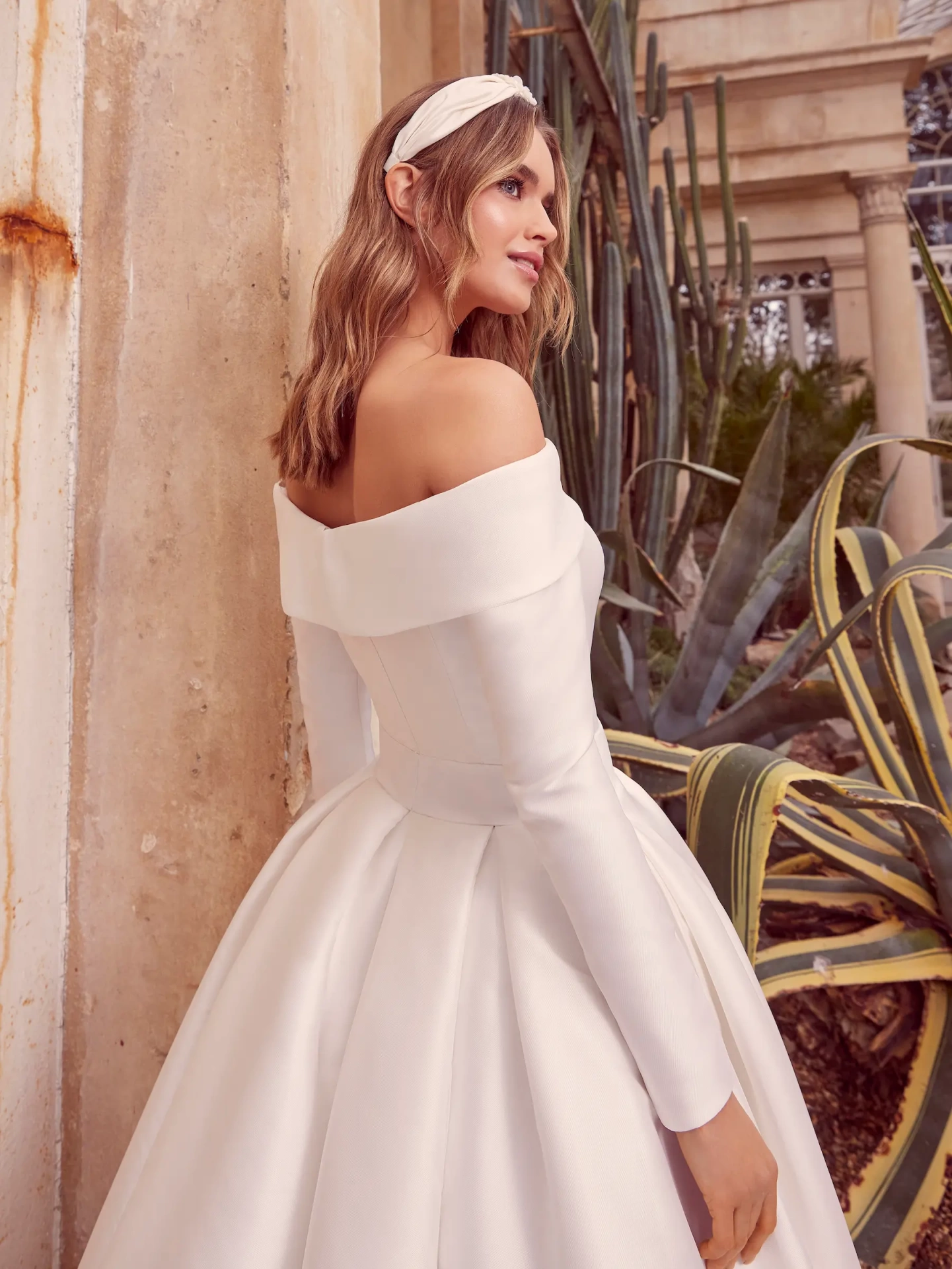 Abito da sposa semplice in mikado con scollo dritto off-shoulder, cintura con fibbia ton-sur-ton, maniche lunghe staccabili, gonna ampia strutturata | Lo Specchio Atelier Abiti da Sposa a Verona