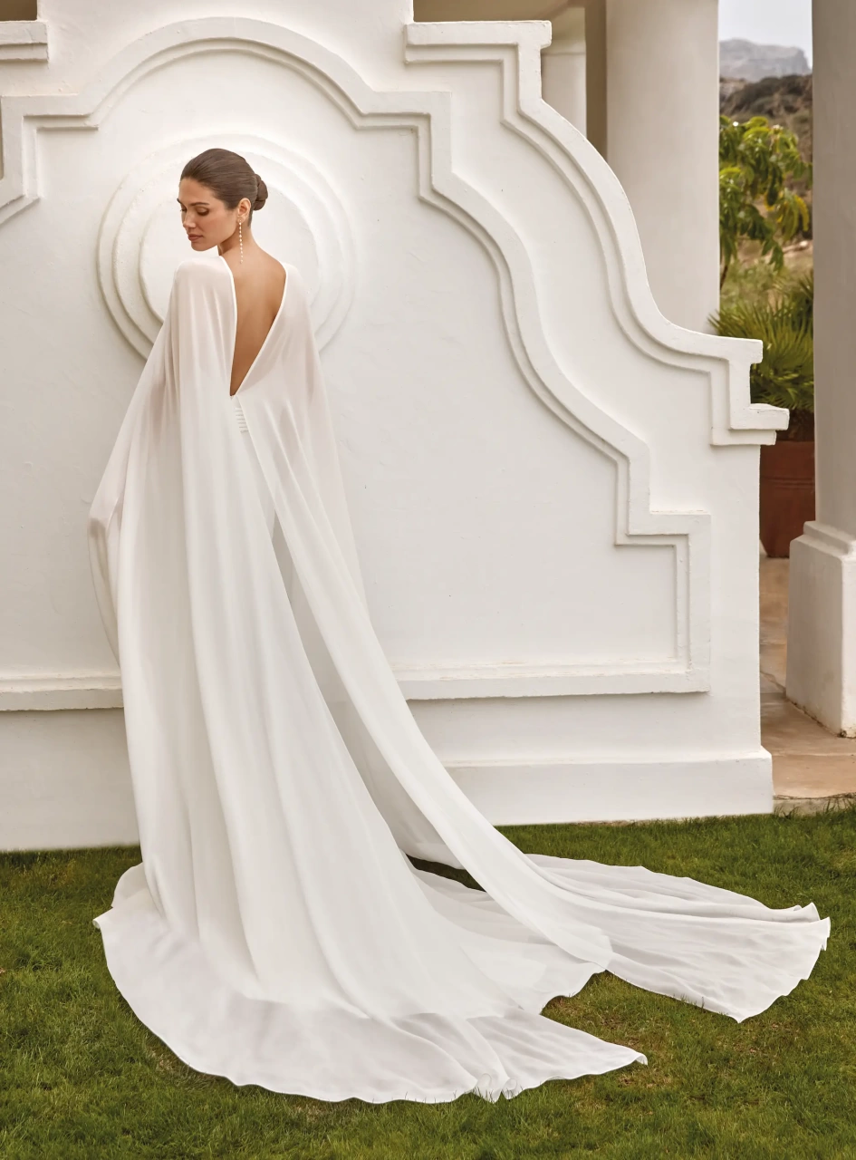 Abito da sposa elegante e raffinato a sirena con scollo all'americana, schiena scoperta, maniche particolari in chiffon che creano un mantello a strascico lungo fino a terra, applicazioni di perle sui fianchi